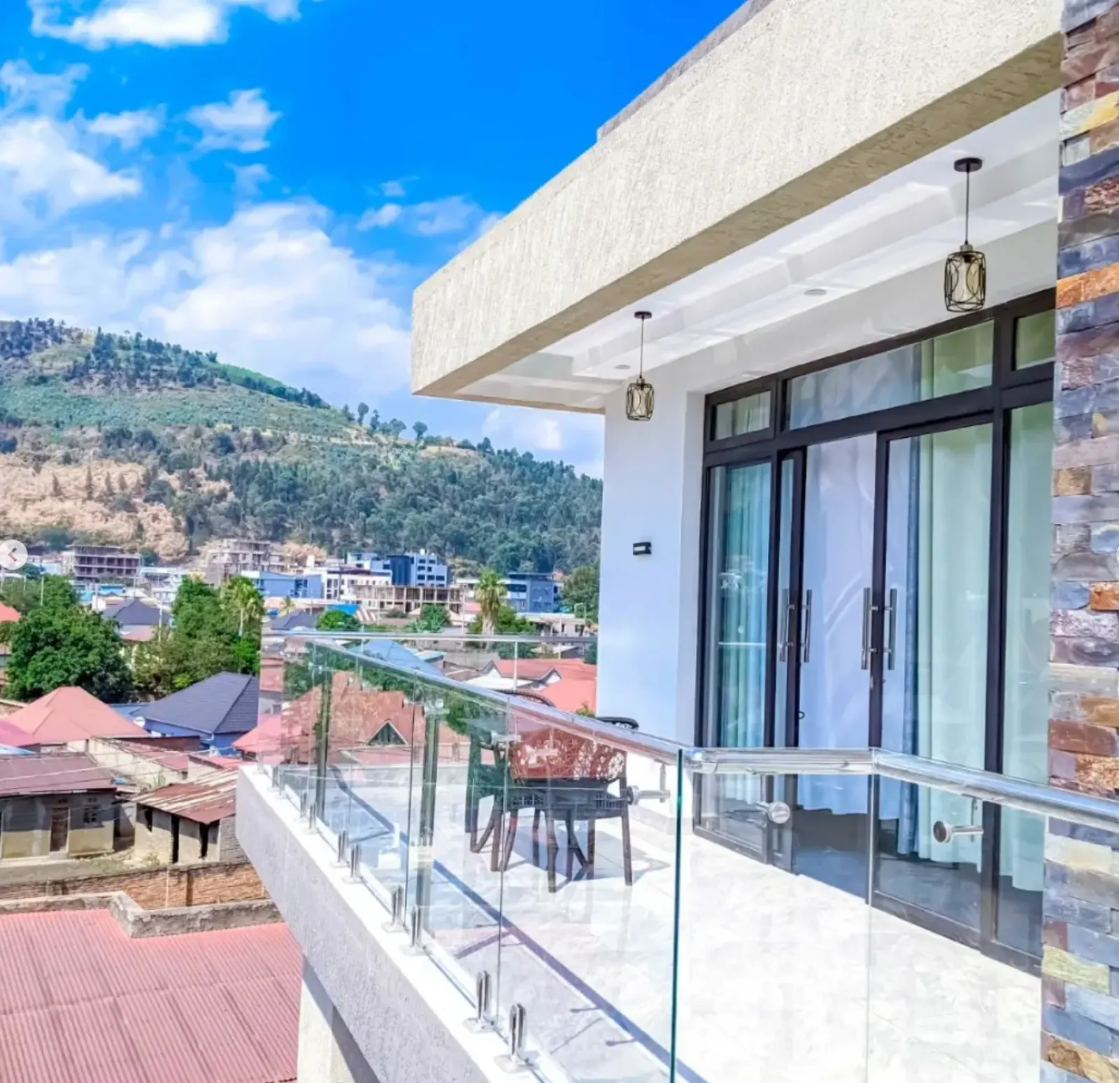 A modern balcony with a glass railing, overlooking Gisenyi and the hills