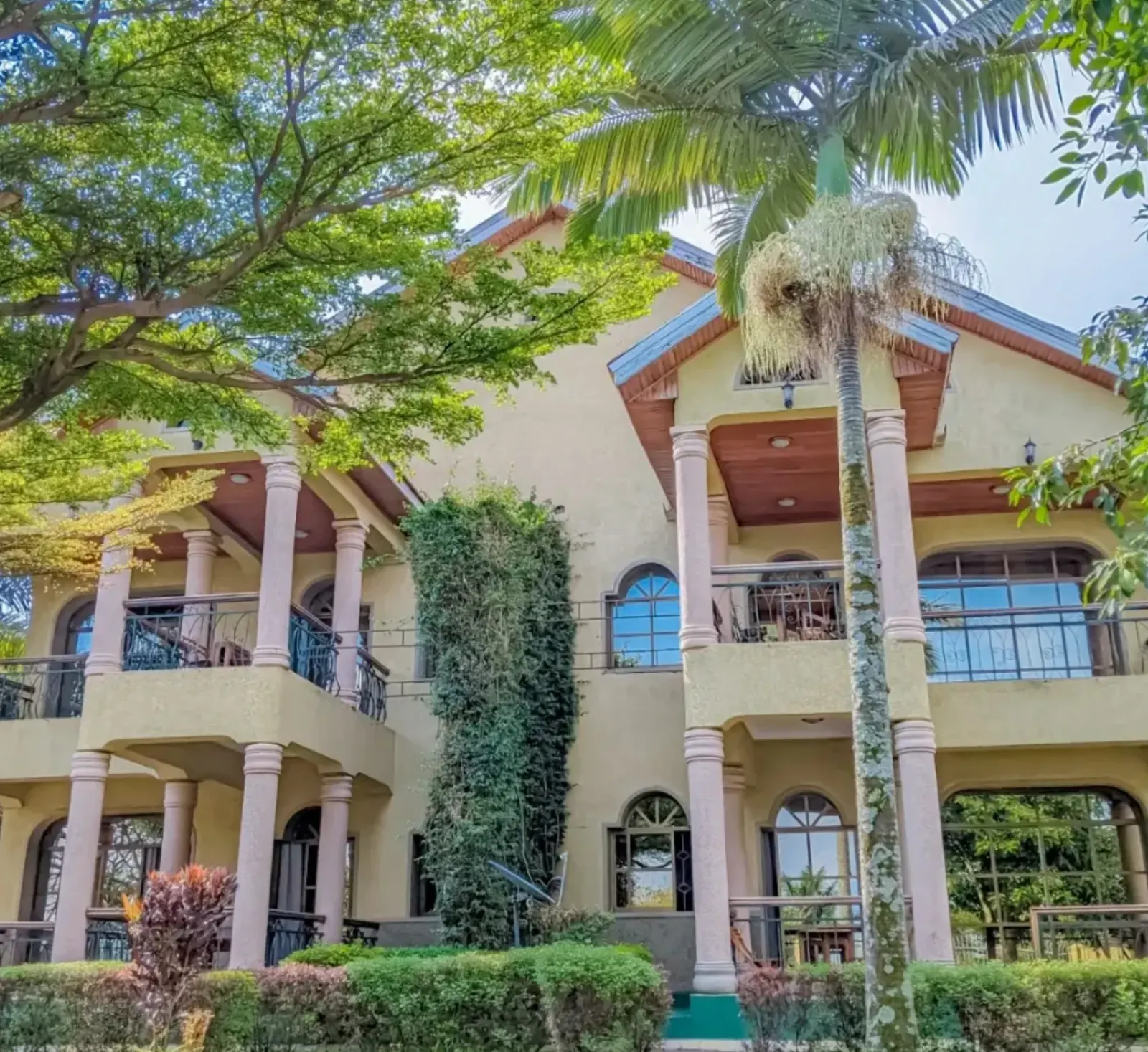 A large cream villa with stone columns, arched windows and balconies